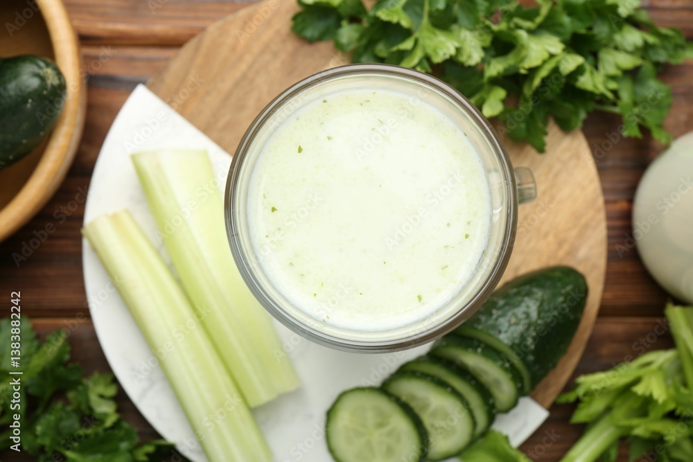 Healthy parsley drink in glass, leaves, celery and cucumber on wooden table, flat lay Healthy parsley drink in glass, leaves, celery and cucumber on wooden table, flat lay