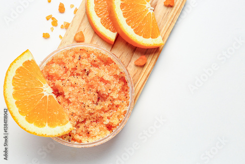 Obraz na płótnie Wooden board with jar of natural body scrub and orange slices on light background, closeup w salonie