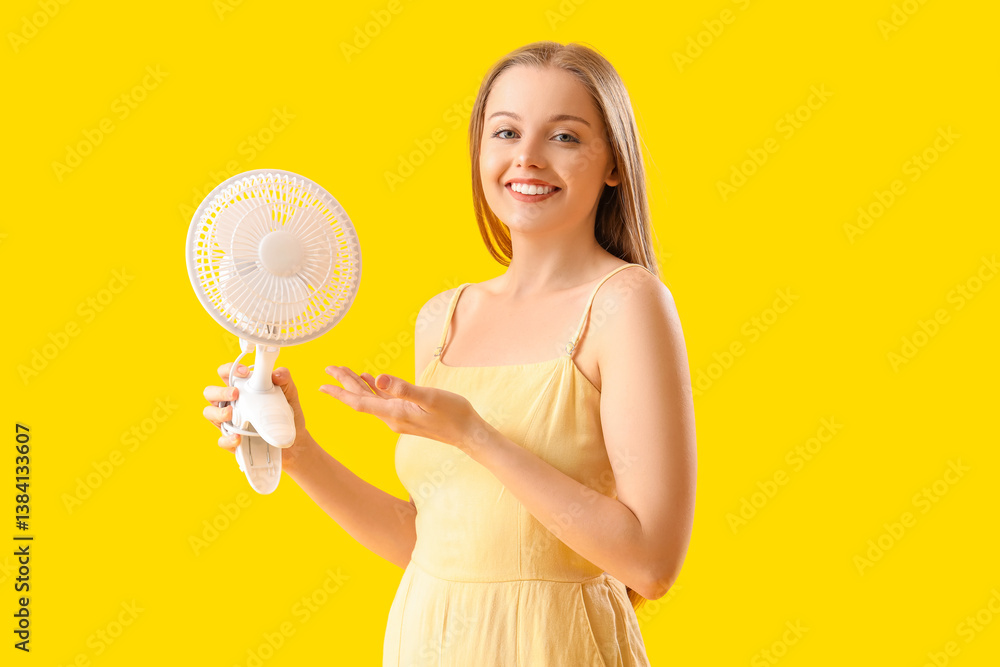 Young woman with electric fan on yellow background Young woman with electric fan on yellow background