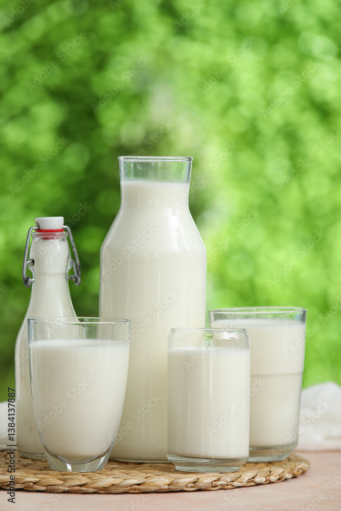Glasses and bottles of fresh milk on beige table outdoors Glasses and bottles of fresh milk on beige table outdoors