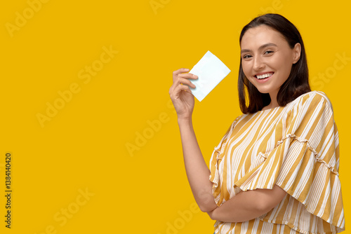 Beautiful young woman with menstrual pad on yellow background