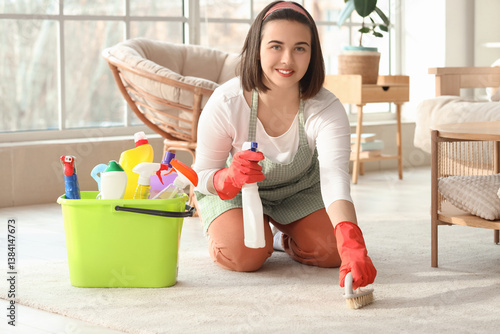 Young woman cleaning carpet...
