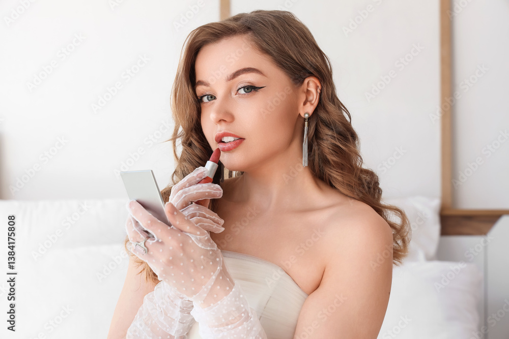 Beautiful bride applying lipstick in bedroom Beautiful bride applying lipstick in bedroom