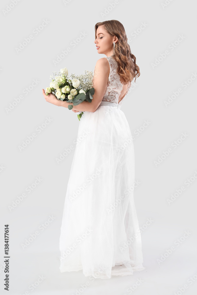 Beautiful bride in white wedding dress with flowers on light background Beautiful bride in white wedding dress with flowers on light background