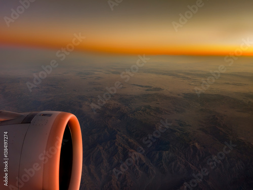 Obraz na płótnie Looking out the window of an airplane with partial wing and engine view with dramatic landscape and sky w salonie