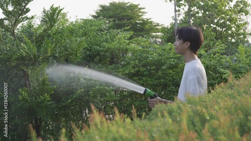 Asian young man watering plants