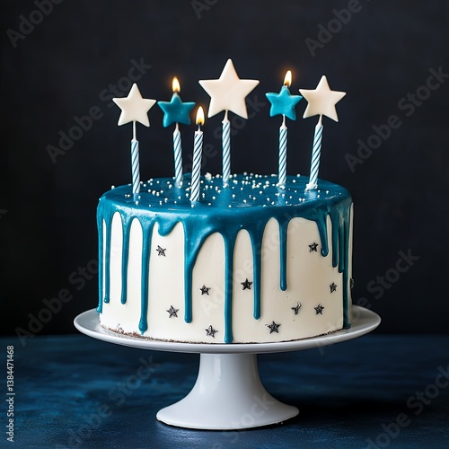 White birthday drip cake with teal ganache, star toppers and fun candles over dark blue background