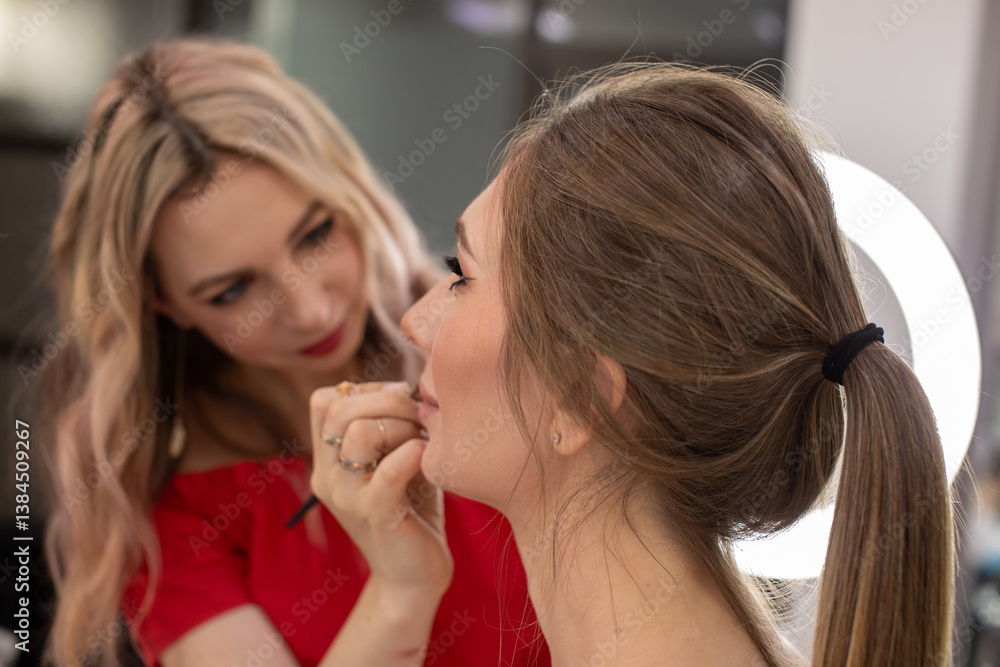 Female makeup artist applying makeup on a client Female makeup artist applying makeup on a client