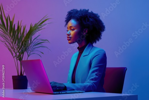 A young Black woman in a blue blazer works on her laptop in a vibrant, neon-lit room.