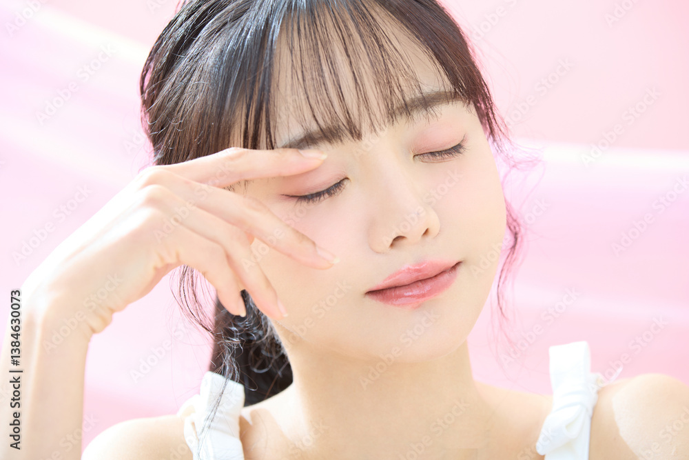 Fototapeta premium ピンク背景で撮影をした若い女性の爽やかな美容イメージ