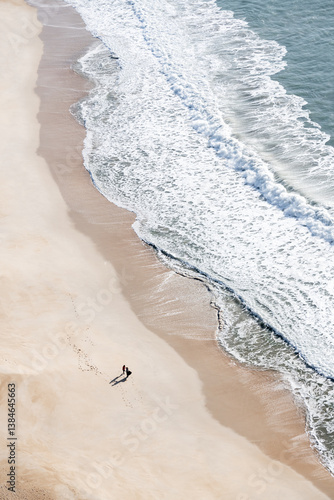 Obraz na płótnie Atlantic ocean coast in Nazare, Portugal. People walking on the beach at sunny day. w salonie