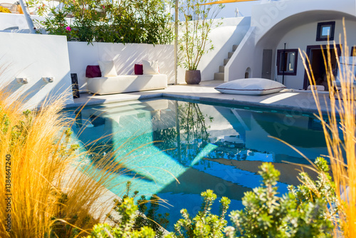 Santorini island, Greece. Luxury swimming pool with blue water and flowers.