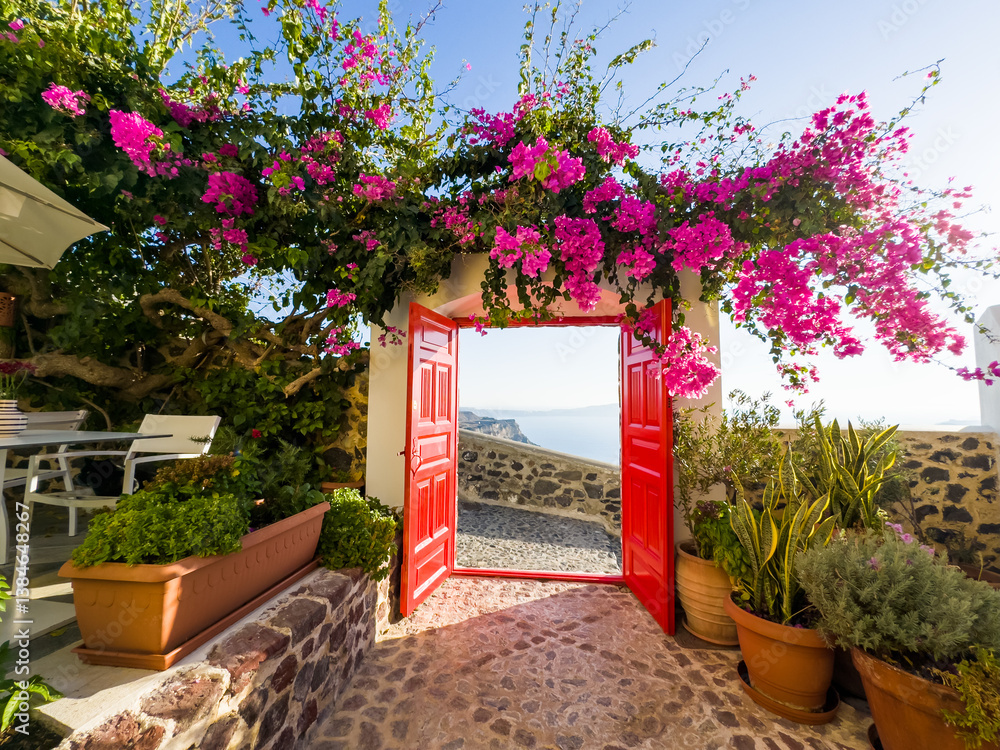 Santorini island, Greece. Beautiful patio with red door and blooming pink flowers.