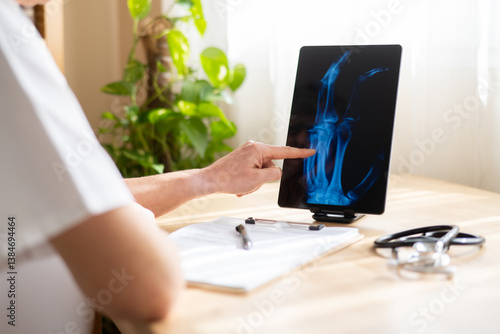 Foto Doctor pointing at a digital tablet displaying a hand x-ray, conducting a medica