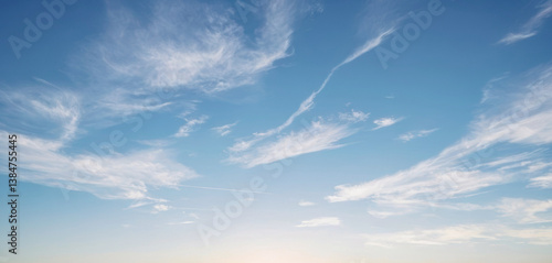 Wide shot of a blue sky with white wispy clouds streaking across it. Background photos for banners, posters and wallpapers.