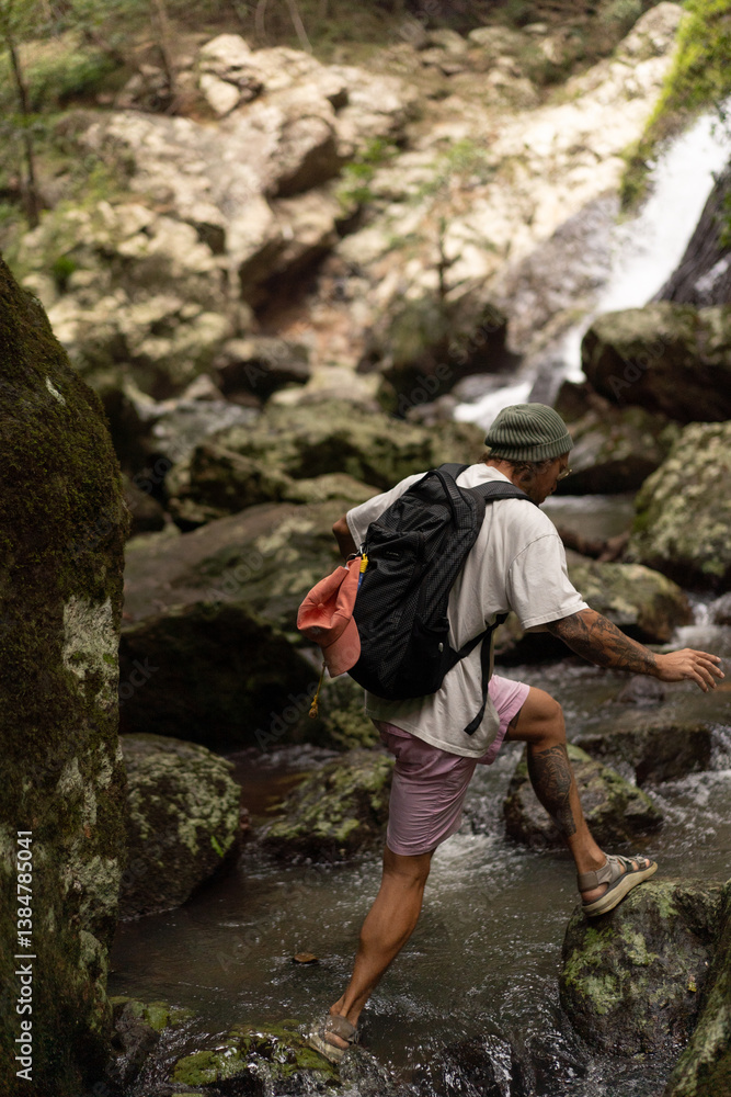 Man hiking over rocks along a waterfall trail in Australia Man hiking over rocks along a waterfall trail in Australia
