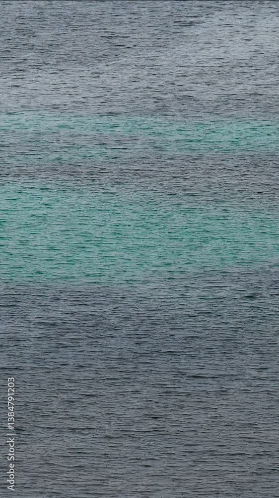 Raindrops hitting the ocean, forming small ripples and a textured surface Raindrops hitting the ocean, forming small ripples and a textured surface
