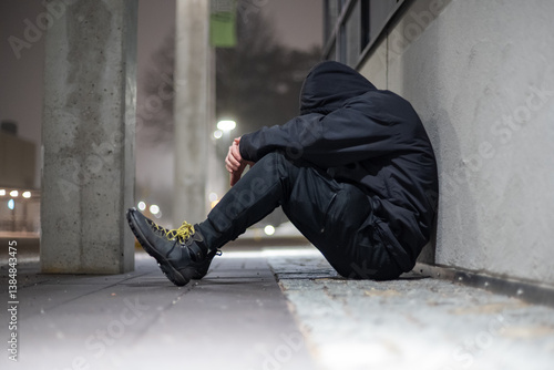 Slika na platnu depressed hooded man sitting on a street during night time.