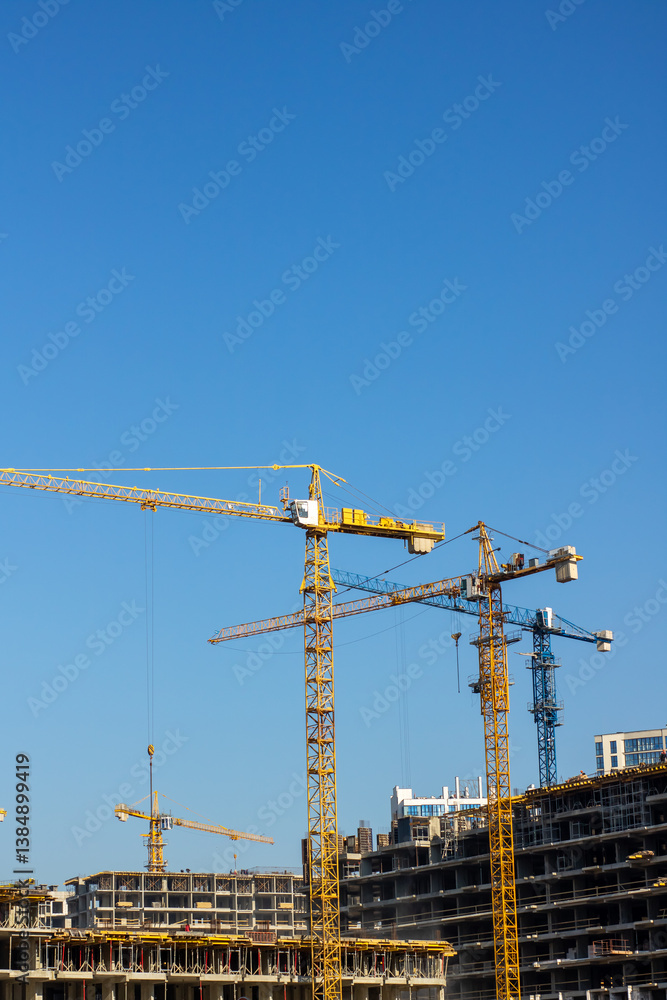 A busy construction site with cranes under a clear blue sky A busy construction site with cranes under a clear blue sky