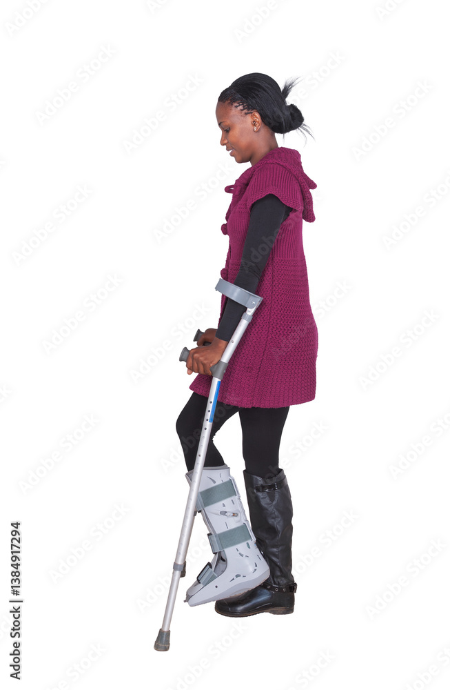 Fototapeta premium Young African Woman Broken Leg Wearing Orthopedic Boot for Leg walking on crutches isolated on white background