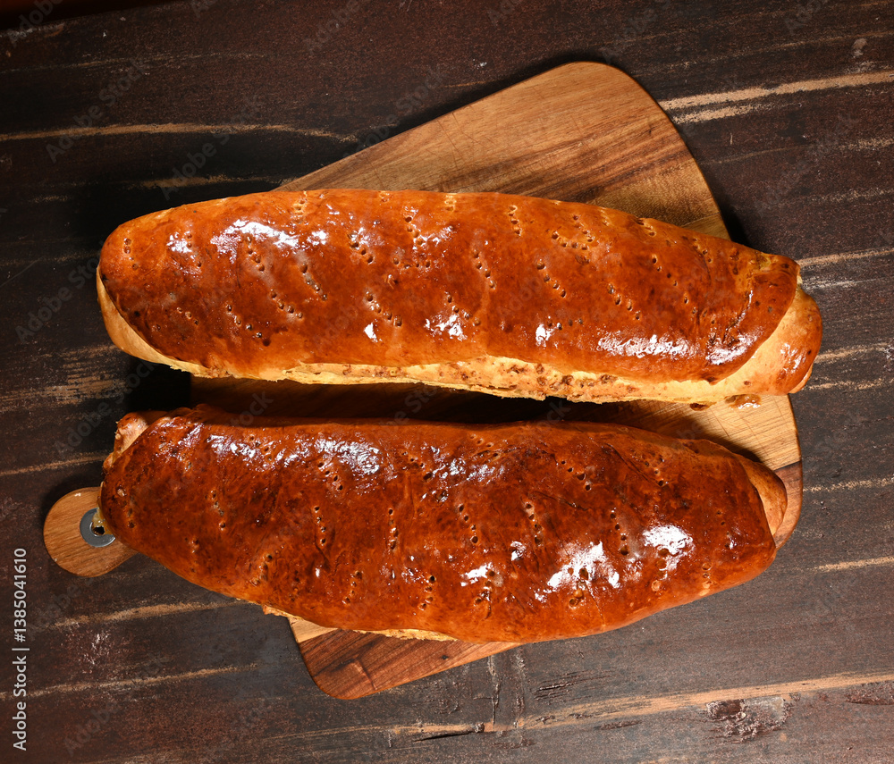 Freshly baked bread rolls on a wooden cutting board displayed in a warm kitchen setting