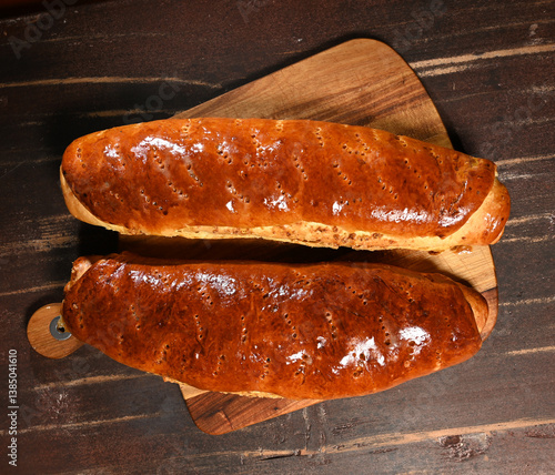 Obraz na płótnie Freshly baked bread rolls on a wooden cutting board displayed in a warm kitchen setting w salonie