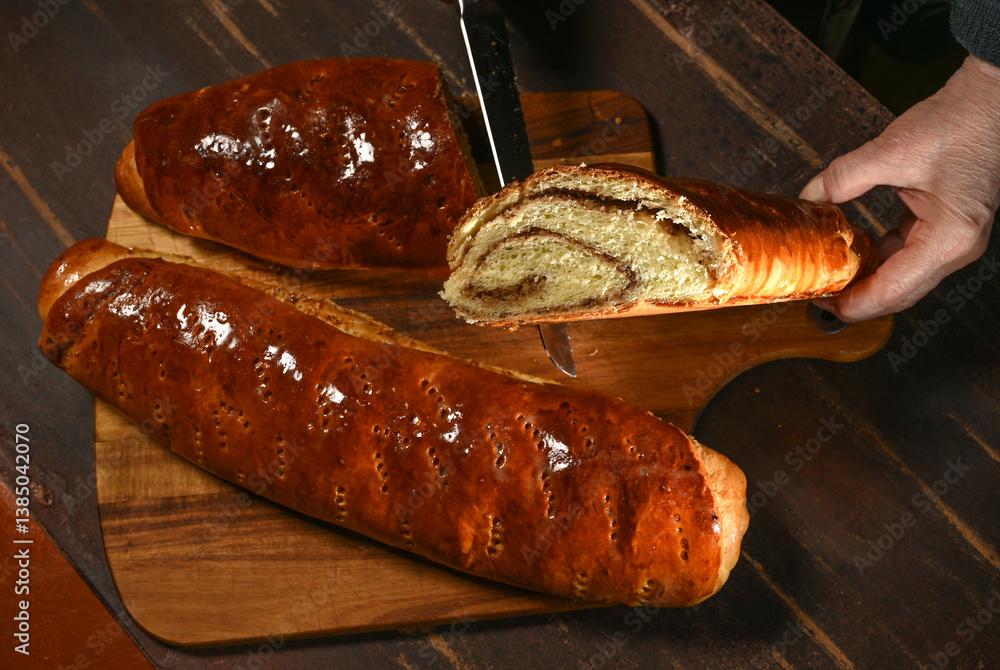 Freshly baked bread being sliced on a wooden board in a cozy kitchen setting during the afternoon