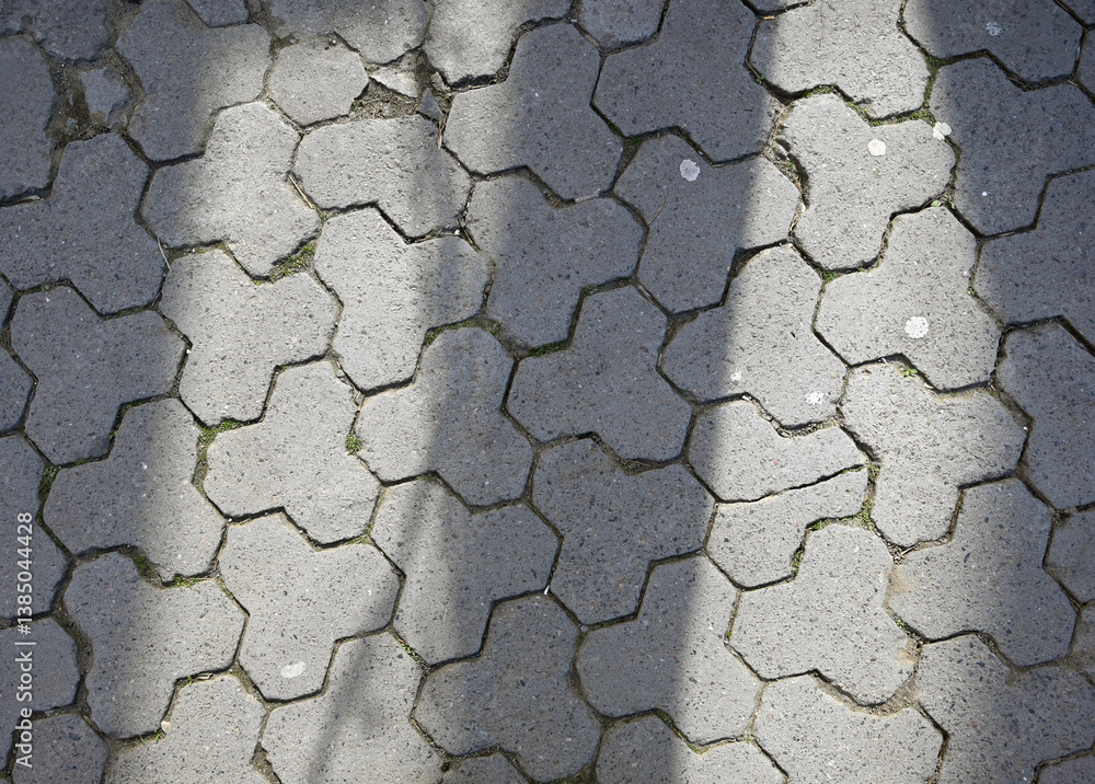 Patterns of light and shadow on textured paving stones in an urban setting during daylight