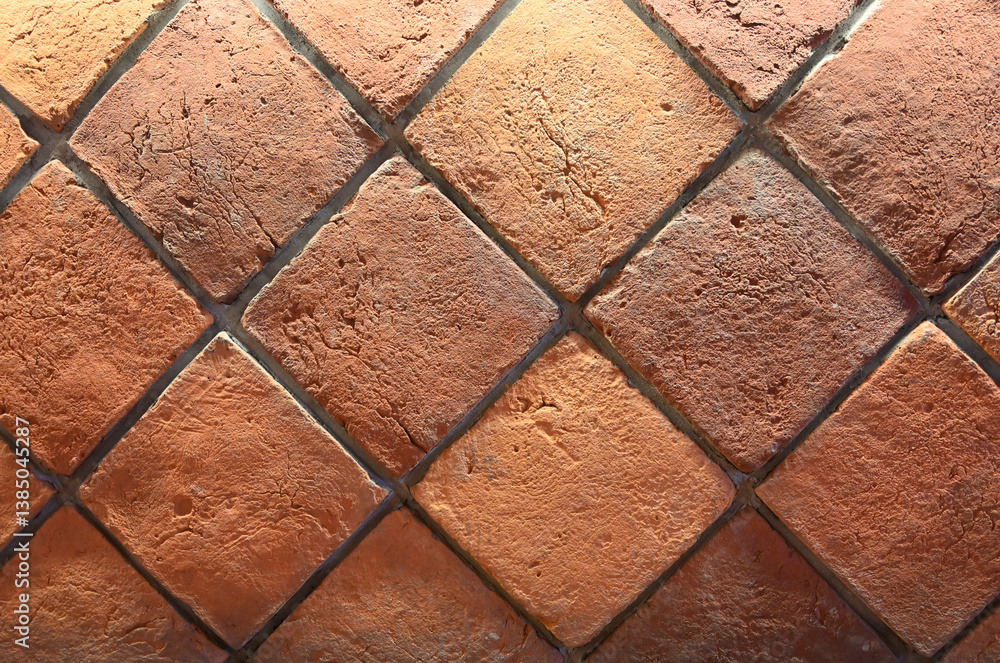 Textured terracotta tiles arranged in a diamond pattern displayed indoors, showcasing an earthy color palette