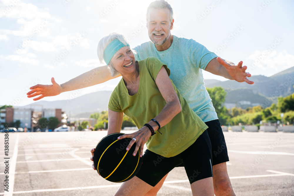 Obraz premium Beautiful happy senior couple playing basketball and having fun - Mature married couple in love bonding outdoors and doing sport together, concepts about elderly lifestyle, relationship and quality of