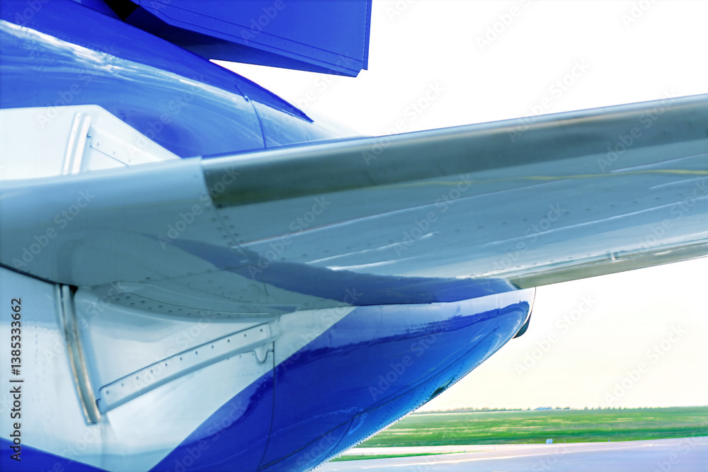 Sleek airplane tail with vibrant blue and white paint, captured on a clear day. Image highlights modern aviation design and engineering precision on the runway
