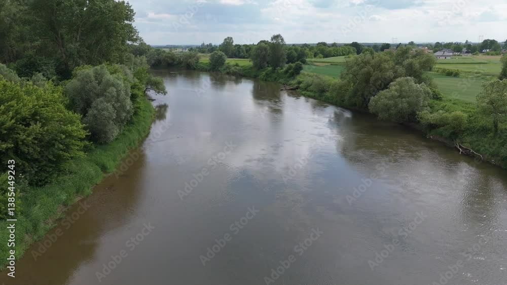 Aerial video of a calm river reflecting drifting clouds, with slow-moving water under green tree-lined banks. Aerial video of a calm river reflecting drifting clouds, with slow-moving water under green tree-lined banks.