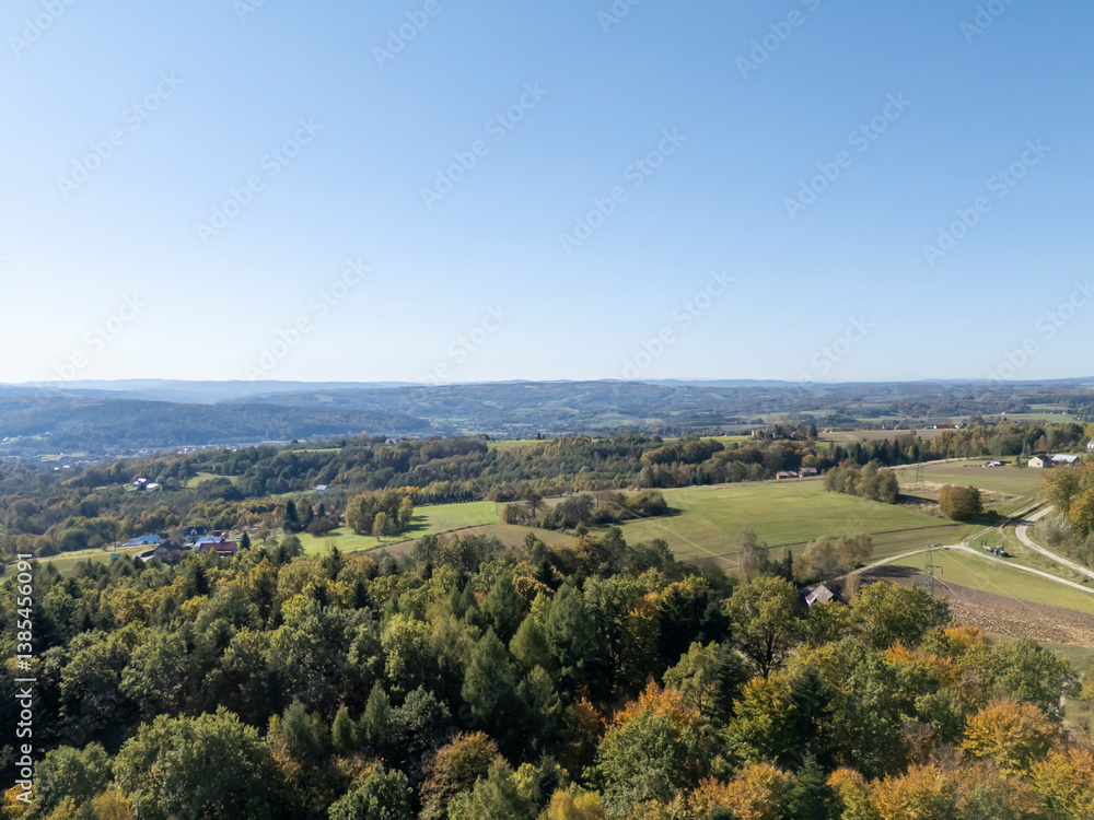 Obraz premium Scenic view of lush green valleys under clear blue sky, showcasing autumn colors in the landscape, ideal for nature-themed projects and editorial content.