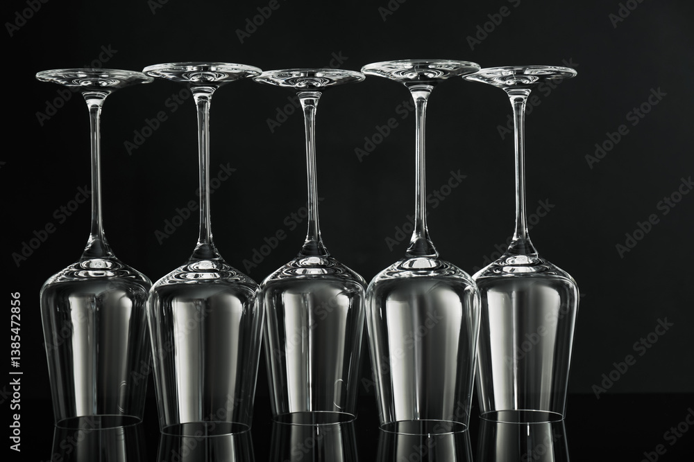 Many empty clean glasses on mirror surface against black background