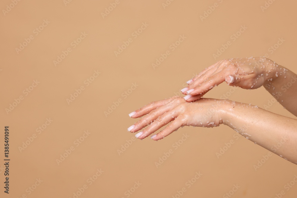 Fototapeta premium Woman applying body scrub onto her hands on beige background, closeup. Space for text