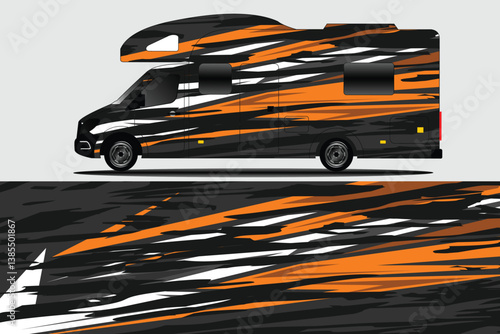 Stylish camper van with dynamic orange and black design parked on a smooth asphalt road