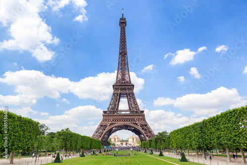 The Eiffel Tower stands tall and majestic against a vivid blue sky, framed by symmetrical green lawns and trimmed trees.