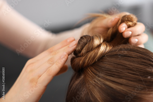 Hairdresser doing girl's hairstyle in salon, closeup
