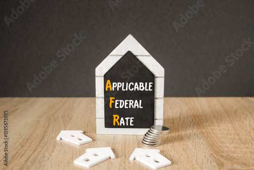 Obraz na płótnie Concept words Applicable Federal Rate on black blackboard. Beautiful wooden table, black background. A stack of coins. Business concept. w salonie