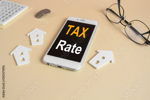 Obraz na płótnie The expression Tax rate on the mobile phone screen. Beautiful beige background. Glasses, miniature houses, coins. Business concept. w salonie