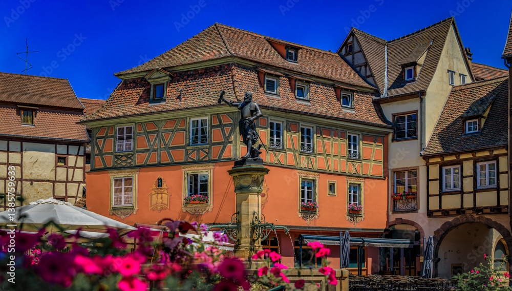 Ornate half timbered houses with blooming flowers near the Schwendi Fountain, Little Venice district in Colmar, picturesque village in Alsace, France