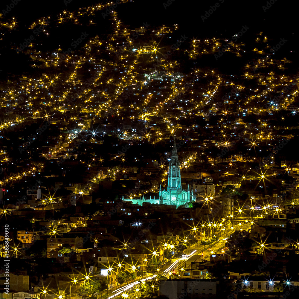 Stunning night view of the Gothic-style church illuminated in Medellín, Medellin, Antioquia, Colombia. City lights create a magical atmosphere with starburst streetlights and a vibrant urban landscape