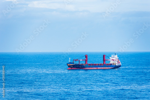 Small cargo ship sailing through calm, blue ocean, on her international trade route.