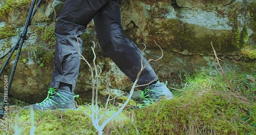Close-Up of Legs in Mountain Boots Walking Through the Forest. The hiker steps confidently along a trail surrounded by nature and fallen leaves.