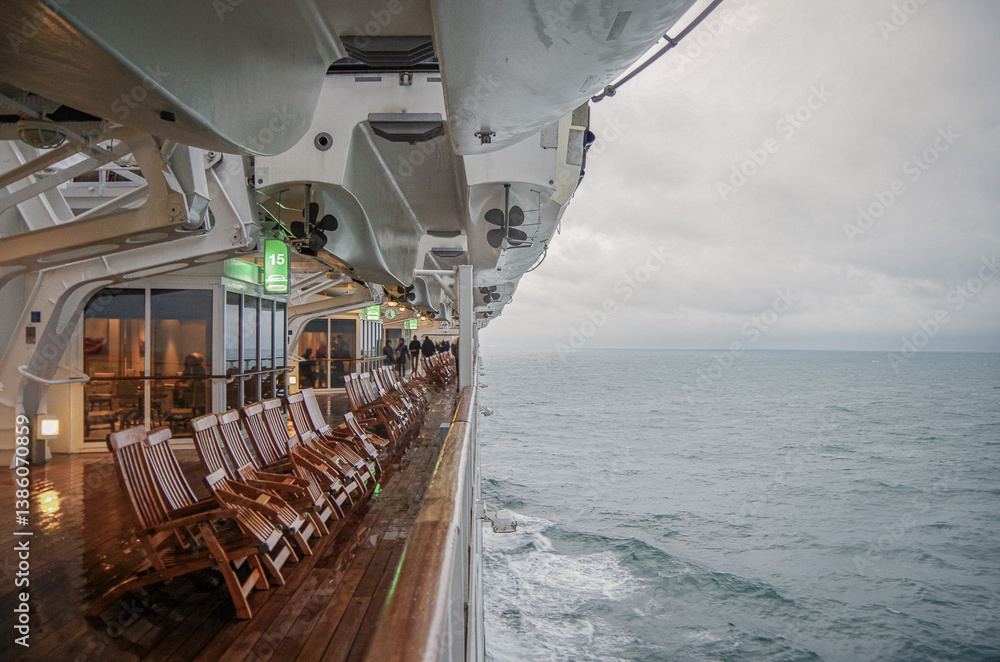 Views onto wet outdoor teak balcony terrace veranda promenade boat deck of ocean liner cruiseship cruise ship with chairs and loungers at sea during