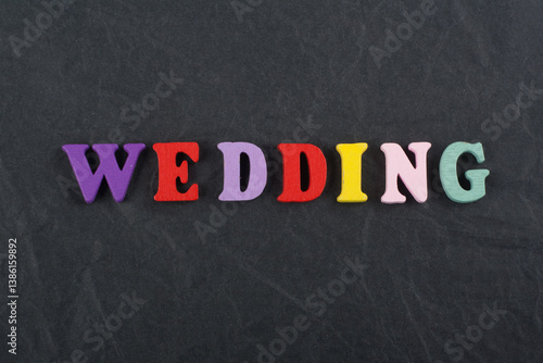 WEDDING word on black board background composed from colorful abc alphabet block wooden letters, copy space for ad text. Learning english concept.