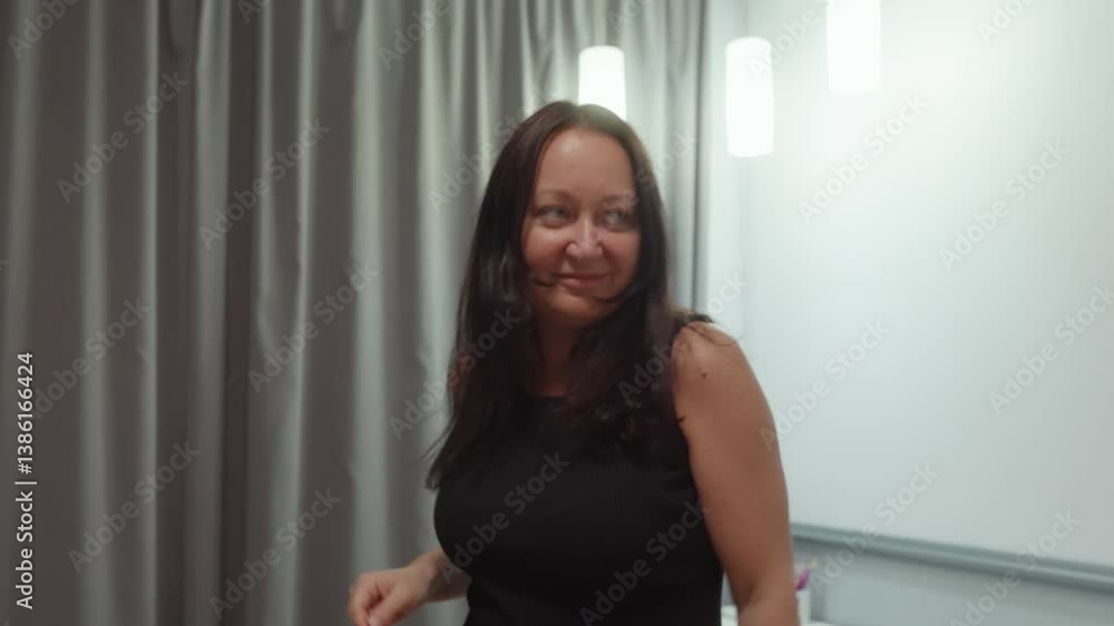 Brunette woman wearing elegant black dress dancing expressively, enjoying leisure moment with joyful movement in cozy indoor space Brunette woman wearing elegant black dress dancing expressively, enjoying leisure moment with joyful movement in cozy indoor space