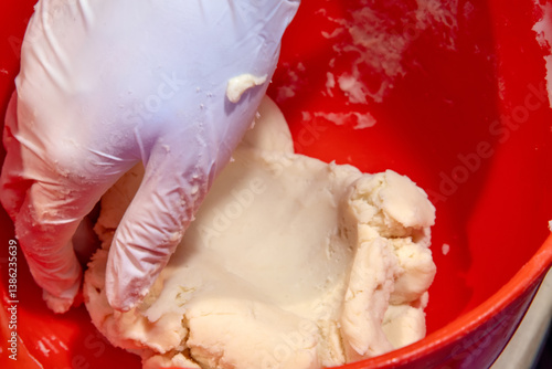 Obraz na płótnie gloved hand mixing dough in a bright red bowl. Close up w salonie