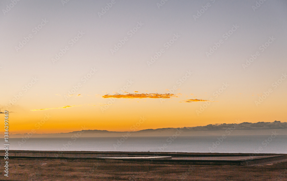 Obraz premium The sky is a beautiful orange color, and the ocean is calm