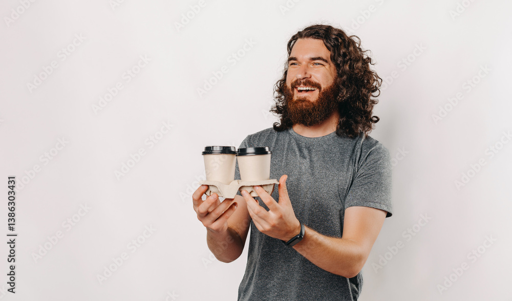 Fototapeta premium A cheerful man joyfully holding two ecofriendly coffee cups, exuding happiness against a clean, vibrant backdrop